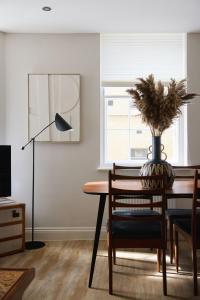 a dining room table with a plant in a vase on it at Superior Stays Luxury Apartments - Bath City Centre in Bath