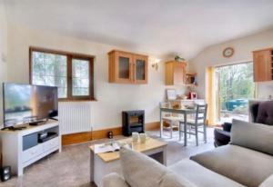 a living room with a couch and a tv and a table at Mountain View Cottage, Hot Tub , Stunning Views in Llanhamlach