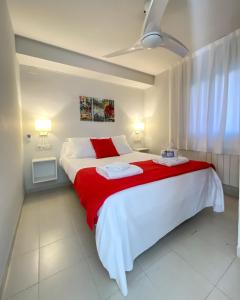 1 dormitorio con 1 cama blanca grande con manta roja en Apartaments Gibert, en Sant Antoni de Calonge