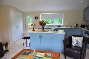 uma cozinha com armários azuis e um balcão com uma cadeira em Alderneuk Lodge em Dumfries