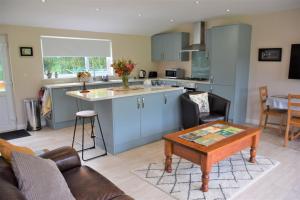 a kitchen and a living room with a table at Alderneuk Lodge in Dumfries