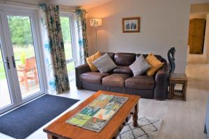 a living room with a leather couch and a table at Alderneuk Lodge in Dumfries