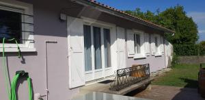 una casa con puertas blancas y un banco en un porche en Maison 2 chambres proche base, en Mont-de-Marsan