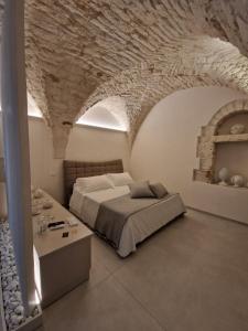 PIRANO Suite e Spa في سيغلي ميسابيكا: غرفة نوم بسرير وجدار حجري