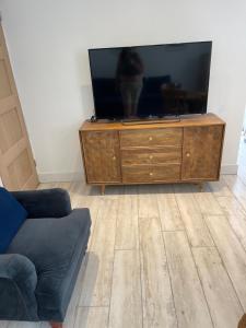 a living room with a flat screen tv on a dresser at Fisherman's Retreat in Wells next the Sea