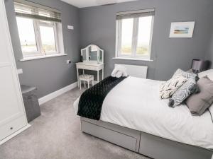 a bedroom with a bed and a table with a mirror at 9 Pilgrims Way in Roch