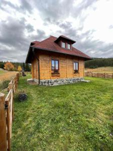 a small wooden house in a field with a fence at Vila Sofija Tornik in Ribnica