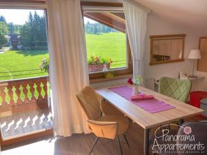 a dining room with a table and a large window at Panorama Appartement inklusive Schladming Dachstein Freizeitcard in Ramsau am Dachstein