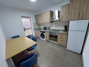 Una cocina con una mesa y un refrigerador blanco. en Acea Nova 3, en Monforte de Lemos