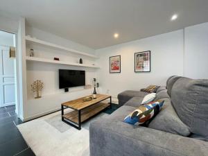 uma sala de estar com um sofá e uma televisão em Le logis BAYA - WEEKEND & HOLIDAY - WIFI & TV em Saint-Vigor-le-Grand