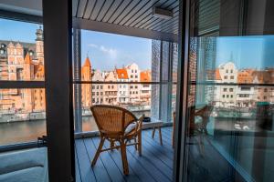 a balcony with a chair and a view of the city at CLASSY APARTMENTS - Gdańsk - Widok z Wyspy in Gdańsk