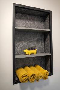 Un estante con toallas amarillas y un juguete amarillo. en Pirnie Lodge Holiday Lets, en Slamannan