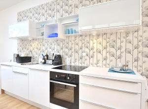a kitchen with white cabinets and a black oven at Como Design-Apartment close to Isar river area - centrally located in Munich