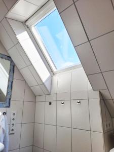 a skylight in a bathroom with white tiles at Wohnung zwischen Nord- und Ostsee mit Fitnessraum in Ostenfeld