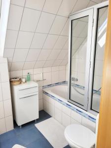 La salle de bains blanche est pourvue d'une baignoire et de toilettes. dans l'établissement Wohnung zwischen Nord- und Ostsee mit Fitnessraum, à Ostenfeld