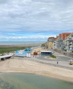 - une vue sur la plage, les bâtiments et l'eau dans l'établissement Les Rameaux, superbe appartement vue mer, Wimereux, à Wimereux