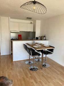 une cuisine avec une table et des chaises dans une pièce dans l'établissement Les Rameaux, superbe appartement vue mer, Wimereux, à Wimereux 6 autres photos