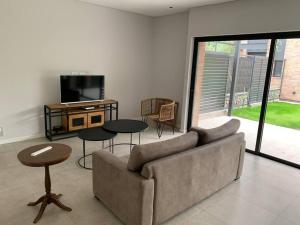 sala de estar con sofá, mesas y TV en Duplex Lujan Mendoza cercanía Chacras de Coria en Luján de Cuyo