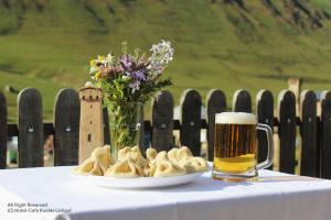 una mesa con un vaso de cerveza y un plato de comida en Hotel-Cafe Koshki Ushguli, en Ushguli