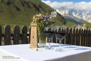 dos copas de vino en una mesa con un jarrón de flores en Hotel-Cafe Koshki Ushguli, en Ushguli