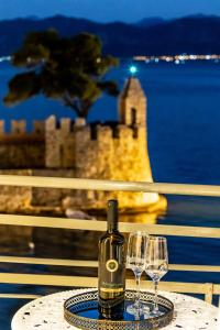 una botella de vino sentada en una mesa con dos copas de vino en Vip Lepanto Port Suites, en Nafpaktos