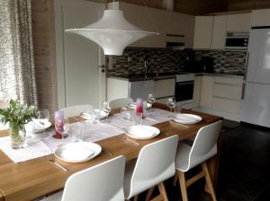 a dining room table with white chairs and a kitchen at Puikkari Raijan Aitta in Mikkeli