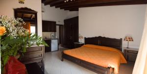 a bedroom with an orange bed and a kitchen at Afrodite Hotel Apartments in Myrina