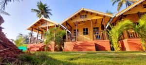 una casa de madera con palmeras delante en Parisa beach resort Tarkarli Bhogwe, en Malvan