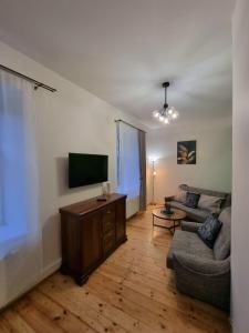 ein Wohnzimmer mit einem Sofa und einem Flachbild-TV in der Unterkunft Cēsu mājas Rīgas ielā in Cēsis