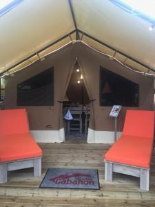 a tent with two red chairs and a table at Oh! Campings - L'Espiguette in Le Grau-du-Roi