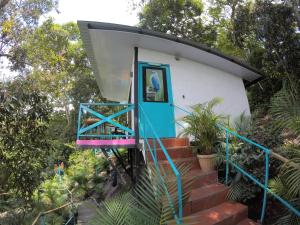 a small house with a blue door on a set of stairs at Waterfall El Paraíso - Cabañas, jacuzzi, piscina y cascada en medio de la naturaleza in Nocaima