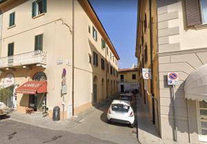 una piccola auto parcheggiata in una strada tra due edifici di Grande appartamento in centro a Pontedera