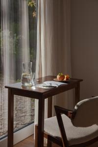 una mesa de madera con un cristal junto a una ventana en A Padaria Farmhouse en Cinfães