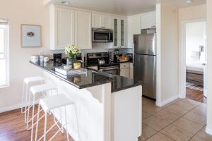 a kitchen with white cabinets and a stainless steel refrigerator at Sonrisa I by AvantStay Bright Pacific Beach Home in San Diego