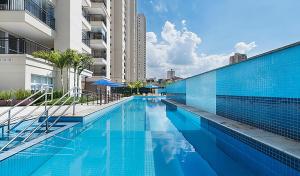 a swimming pool next to a tall building at Bright Studio - GRU in Guarulhos