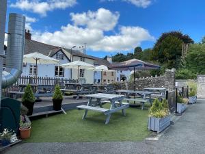 un grupo de mesas de picnic y sombrillas frente a un edificio en The Swan Hotel en Kington