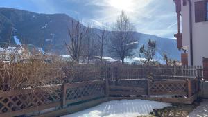 a fence with snow on it with mountains in the background at Hernegg Apartment in Riscone