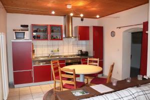 eine Küche mit roten Schränken und einem Tisch in der Unterkunft Fachwerkhaus Maxen in Müglitztal