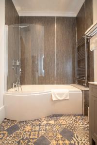 Gordonston Apartments في إينفيرنيس: حمام مع حوض استحمام وأرضية من البلاط