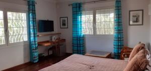 um quarto com cortinas azuis, uma cama e uma secretária em Chambre d'Hôte Villa Maritampona em Antsirabe