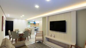 a living room with a table and a television on a wall at Apartamento completo - Vila A in Foz do Iguaçu