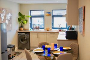 a kitchen with a table and a kitchen with a washing machine at Chatham Serviced Apartments by Hosty Lets in Chatham