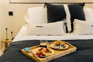 a tray with food and drinks on a bed at Host Inn Le Lumiere SPA & CINÉMA in Lyon