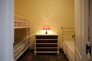 a bedroom with two bunk beds and a lamp on a dresser at A Janela do Alentejo in Campinho