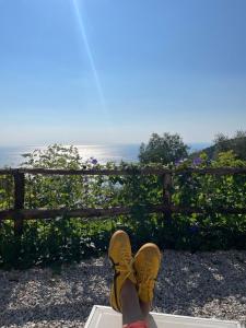 een persoon met zijn voeten op een bank die naar de oceaan kijkt bij Amalfi Coast - Mini Cottage vista mare con giardino in Vietri