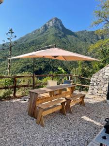 een houten picknicktafel met een parasol en stoelen bij Amalfi Coast - Mini Cottage vista mare con giardino in Vietri