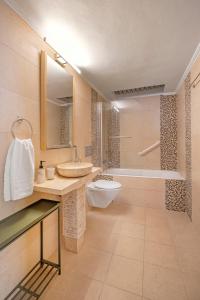 a bathroom with a sink and a toilet and a tub at Filigrana Villa Lindos in Lindos