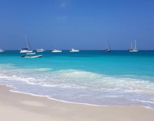 a beach with boats in the water and some sand at Frangipani House Nungwi Zanzibar in Nungwi