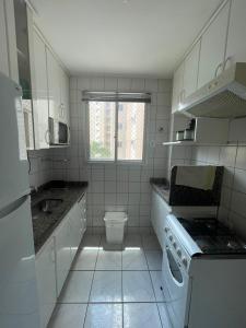 - une cuisine carrelée de blanc avec un lavabo et des toilettes dans l'établissement Caldas Novas Ecologic Park Thermas Apartamento, à Caldas Novas