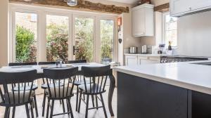 a kitchen with a counter and a table with stools at Grooms Lodge, Chipping Campden - Taswell Retreats in Chipping Campden